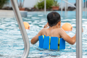 Bild vergr&ouml;&szlig;ern: Kind mit Schwimmhilfe im Schwimmbecken.