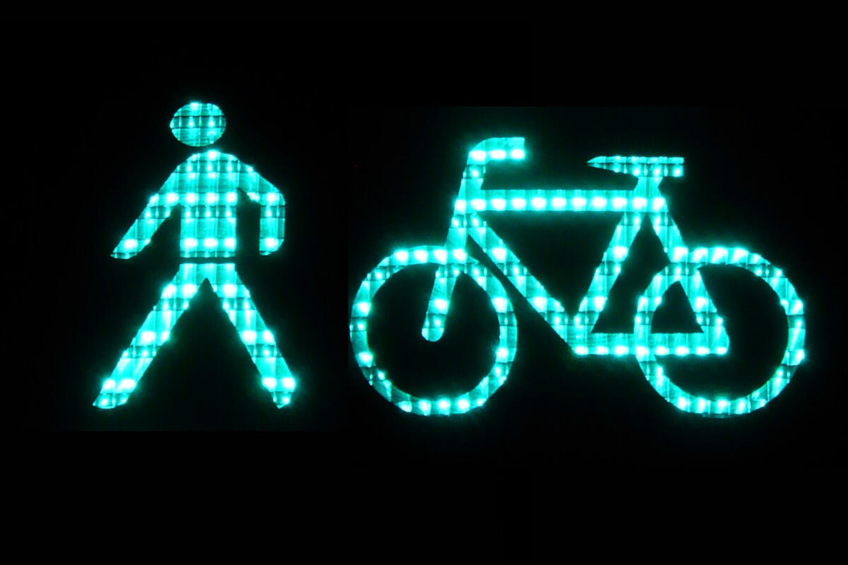 Grün leuchtende Zeichen des Radfahrers und Fußgängers einer Ampel.