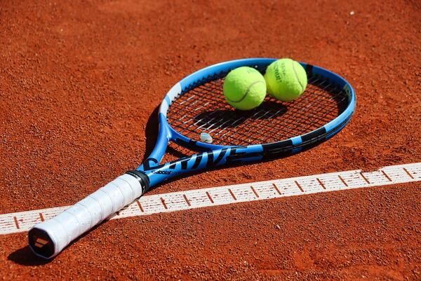 Liegender Tennisschläger, auf dem sich zwei Tennisbälle befinden.