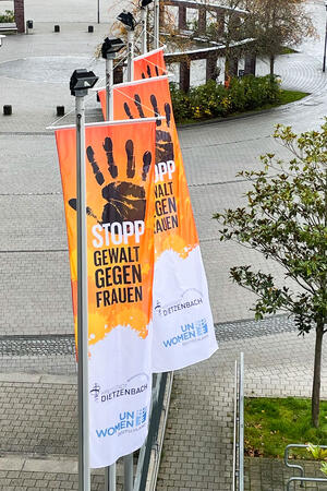 Bild vergrößern: Orangefarbene Flaggen mit dem Aufdruck "Stopp Gewalt gegen Frauen"