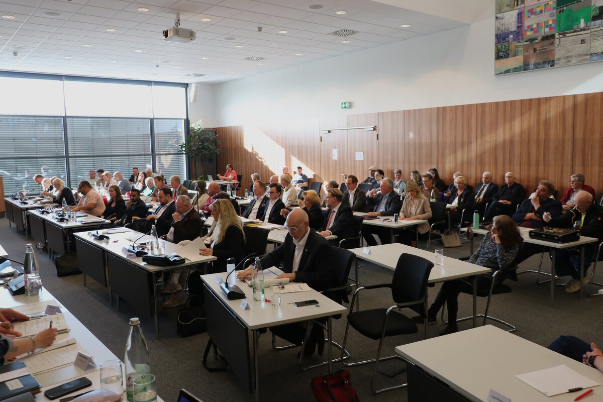Frauen und M&auml;nner an Tischen sitzend in einem Konferenzsaal