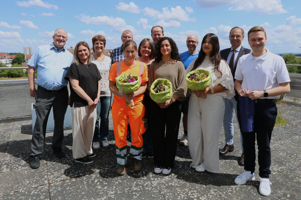 Eine gro&szlig;e Personengruppe von M&auml;nnern und Frauen. In der ersten Reihe stehen vier junge Frauen und ein Mann mit Blumenstrau&szlig; in der Hand - dies sind die Ausbildungsabsolventen.