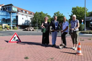 Bild vergr&ouml;&szlig;ern: Das Werkzeug steht symbolisch parat f&uuml;r die n&auml;chsten Entsiegelungsma&szlig;nahmen in Dietzenbach - los geht es im August 2026 am Steinberg-Kreisel: Nacheinander werden an f&uuml;nf Standorten betonierte Fl&auml;chen zur&uuml;ckgebaut, Baumscheiben vergr&ouml;&szlig;ert und neue Gr&uuml;nfl&auml;chen geschaffen. Im Bild am Steinberg-Kreisel: Dr. Tanja Langhans (Klimaschutz), Dr. Dieter Lang (B&uuml;rgermeister), Stefan Rogge (Bereichsleiter Gr&uuml;nfl&auml;chen, St&auml;dtische Betriebe), Christine Kummerow (Abteilung Umwelt und Forst, St&auml;dtische Betriebe)