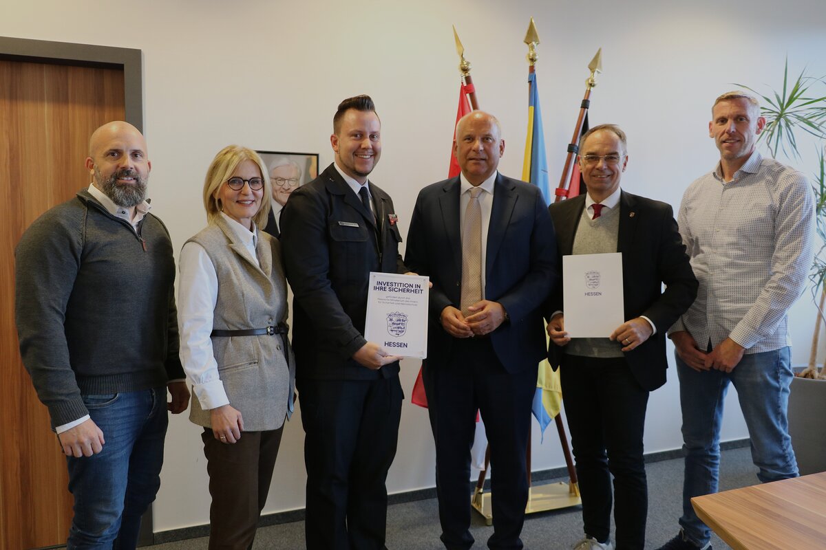 Innenminister Roman Poseck zwischen Stadtbrandinspektor Michael Henke sowie B&uuml;rgermeister Dr. Dieter Lang; weiterhin Markus Hockling, Fachbereichsleiter Sicherheit & Ordnung (links), Monika R&uuml;hr, Fachbereichsleiterin Bau- & Immobilienmanagement, und Matthias Marx, Abteilungsleiter Brand-, Katastrophen- & Zivilschutz (rechts).