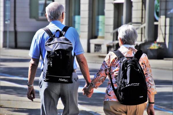 Ein Senior und eine Seniorin halten sich an den Händen und laufen in der Fußgängerzone